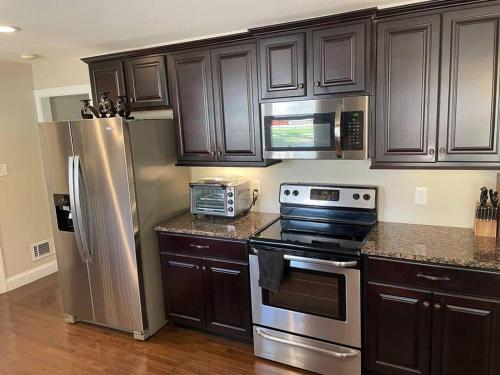 a kitchen with wooden cabinets and stainless steel appliances at Amazing Location - Walk Across To North Hills in Raleigh
