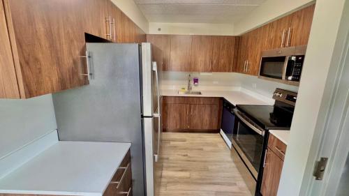 a kitchen with wooden cabinets and a stainless steel refrigerator at Sleep Inn Oakbrook Terrace - Chicago in Oakbrook Terrace