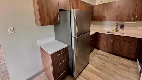 a kitchen with a stainless steel refrigerator and wooden cabinets at Sleep Inn Oakbrook Terrace - Chicago in Oakbrook Terrace