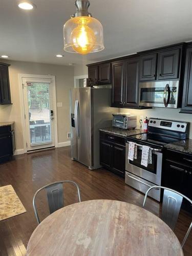 a kitchen with a table and a stainless steel refrigerator at Amazing Location - Walk Across To North Hills in Raleigh
