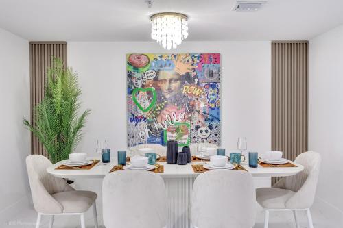 a dining room with a white table with chairs and a painting at Lux 3BR City-View Retreat in Hollywood, 3rd Floor in Hollywood