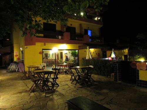 a group of tables and chairs in front of a building at night at Pousada Casa na Praia in Ubatuba
