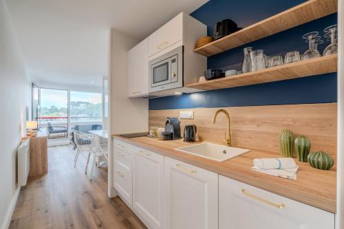 una cucina con armadi bianchi e piano di lavoro con lavandino di Bulles de la Marina - Balnéo a Capbreton