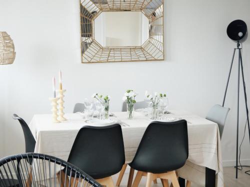 une table blanche avec des chaises noires et un miroir dans l'établissement Deauville Élégance - Chic & Spacieux - Tout à pied, à Deauville