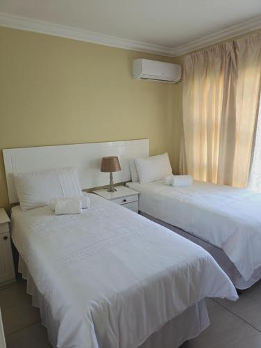 two white beds in a room with a window at SammyGrace Holiday Home in Tzaneen