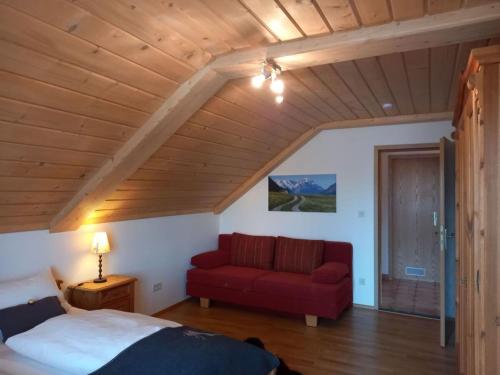 a bedroom with a red bed and a red couch at Holiday apartment Bräu in Riegsee