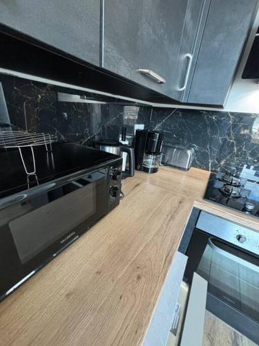 une cuisine avec un plancher en bois et des appareils électroménagers noirs dans l'établissement Logement cosy hyper centre, à Dunkerque