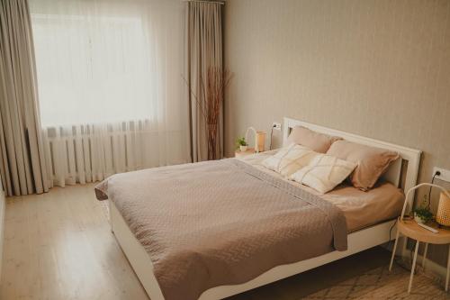 a bedroom with a white bed with pillows and a window at Haustory Apartment in Klaipėda