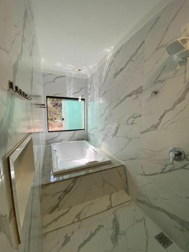a white bathroom with a sink and a window at Pousada Cigarras da Serra in Serra do Cipo
