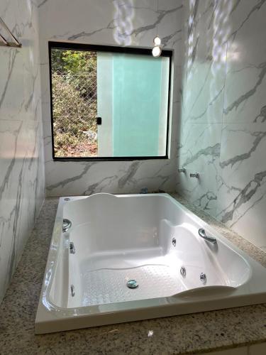 a white bath tub in a bathroom with a mirror at Pousada Cigarras da Serra in Serra do Cipo