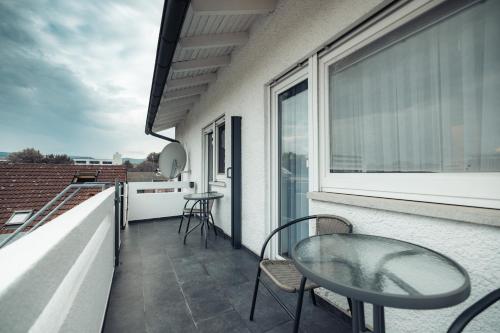 a balcony with a glass table and chairs on a building at Three Corners in Grenzach-Wyhlen