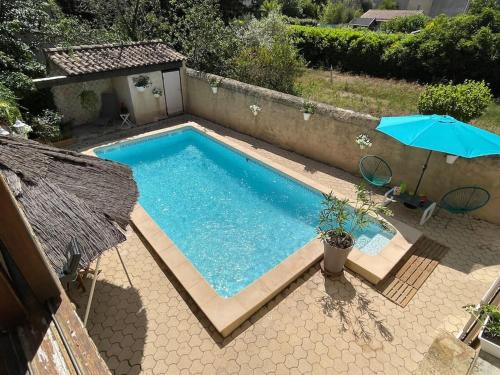 - une piscine avec un parasol à côté d'une maison dans l'établissement Grand studio avec piscine au coeur du village, à Le Puy-Sainte-Réparade