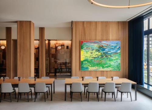 a conference room with tables and chairs and a painting at ROOST Detroit in Detroit