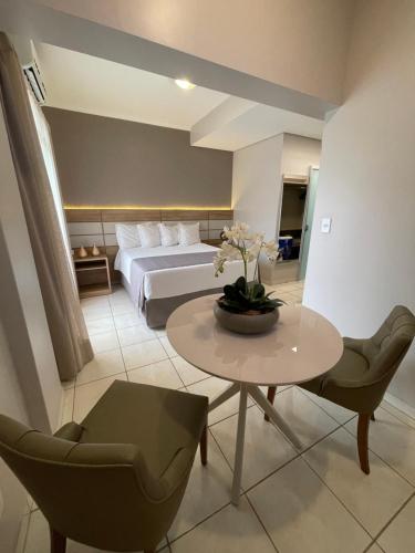 a bedroom with a bed and a table and chairs at Hotel Capital Das Pedras in Teófilo Otoni
