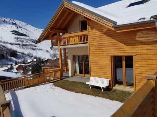 a wooden house with a bench in the snow at Chalet Sapinou in Les Deux Alpes