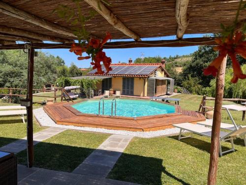 a pool with a wooden deck and a house at Casa delle Viole in Terranuova Bracciolini