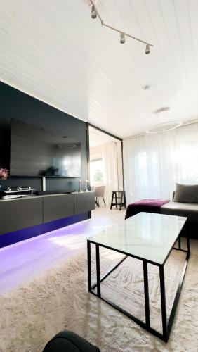 a living room with a glass table and a couch at Rubin Apartment - moderni huoneisto lähellä keskustaa in Kajaani