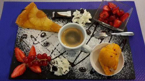 a plate of food with fruit and a cup of coffee at Hôtel Restaurant Le Relais de l'Estuaire in Étauliers