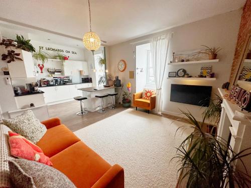 a living room with an orange couch and a kitchen at Penthouse Seaview Warrior Square in Hollington