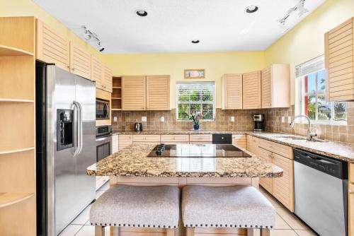 a kitchen with wooden cabinets and a island with two stools at Siesta Key Village, Heated Pool, Beach Access 4 min Walk, 3bdr in Siesta Key