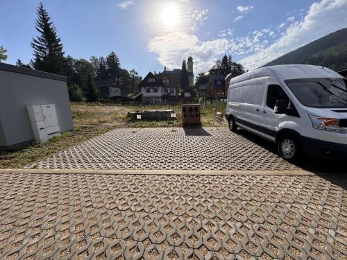 a van is parked in a parking lot at Luxusní apartmán GRAND v centru Harrachova se saunou, wallboxem EV, parkováním zdarma, Netflix a HBO, velkým balkonem a výhledem na Čertovu horu ,sjezdovku a skokanské můstky in Harrachov