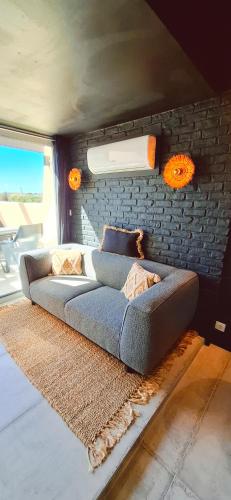 - un canapé dans une chambre avec un mur en briques dans l'établissement Village naturiste Cap d'Agde le Too Hot Coursives, au Cap d'Agde