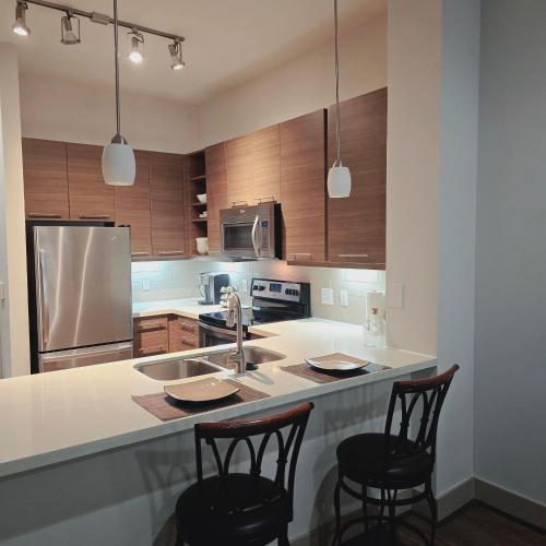 a kitchen with a sink and two bar stools at Midtown Downtown Breeze in Houston