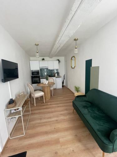 un salon avec un canapé vert et une cuisine dans l'établissement Au coeur de la baie, à Saint-Valery-sur-Somme