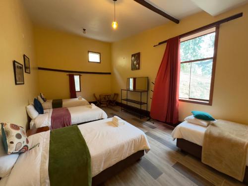 a bedroom with three beds and a window at Ecoterra Inka Lodge Shared Rooms in Quillabamba