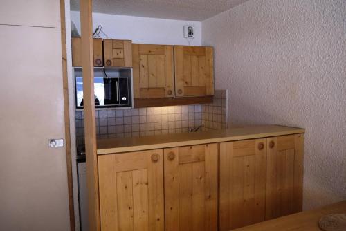 - une cuisine avec des placards en bois et un four micro-ondes dans l'établissement Résidence Arpasson - ARPASSON 18 MAE-4401, à Les Allues