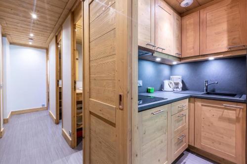 une cuisine avec des armoires en bois et un évier dans l'établissement Résidence Arpasson - ARPASSON 22 MAE-4411, à Les Allues
