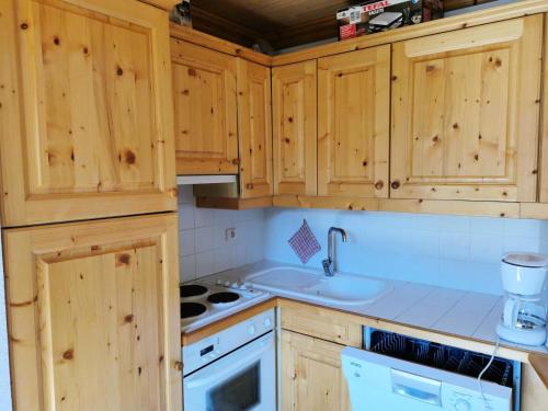 une cuisine avec des armoires en bois et un évier dans l'établissement Résidence Moraine - MORAINE 21 MAE-4481, à Les Allues