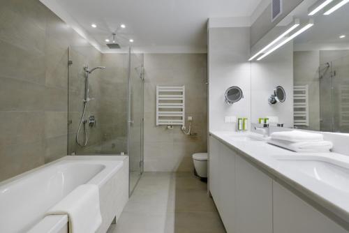 La salle de bains est pourvue de 2 lavabos, d'une baignoire et d'une douche. dans l'établissement STRADONIA Serviced Apartments, à Cracovie