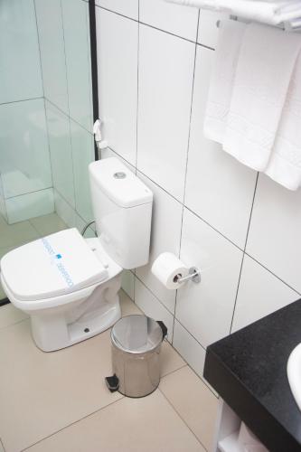 a white bathroom with a toilet and a trash can at Citi Executivo Hotel in Parnaíba