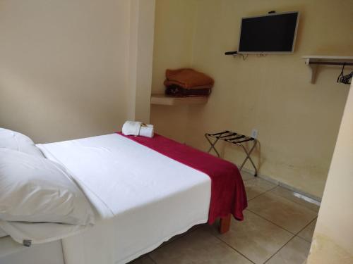 a bedroom with a white bed with a red blanket at Caminito in Santo Antônio do Pinhal