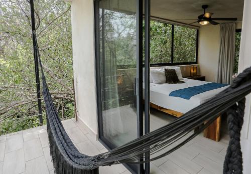 a hammock in a room with a bed and windows at Sunset House in Tulum