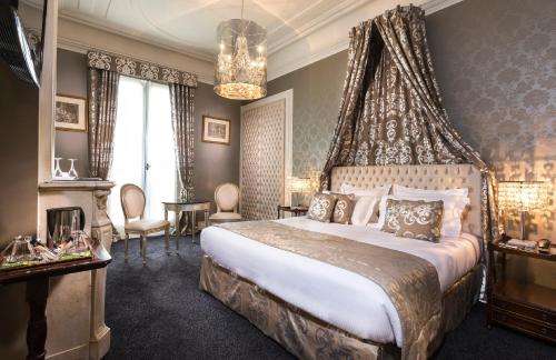 um quarto com uma cama grande e um lustre em Hotel Claridge Paris em Paris