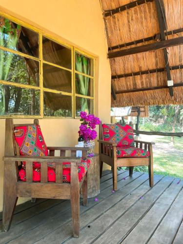 a porch with two chairs and a table with flowers at Nsobe Game Camp in Masaiti