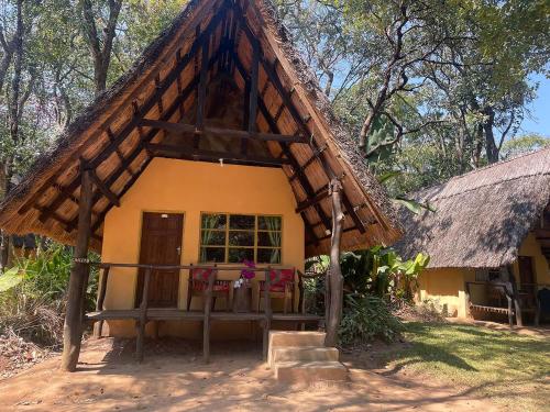 a small yellow house with a thatched roof at Nsobe Game Camp in Masaiti