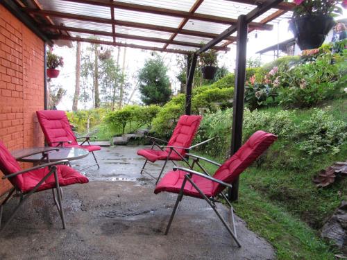 a group of red chairs and a table in a patio at El Barranquero cabaña La Tangara in Cali