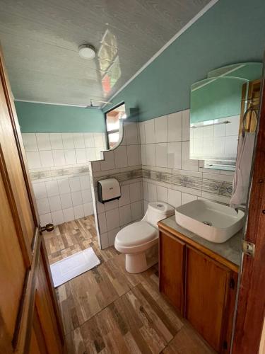 a bathroom with a toilet and a sink and a mirror at Cabinas La Catarata in Fortuna