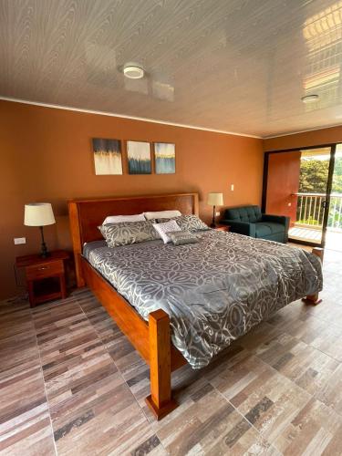a bedroom with a large bed and a balcony at Cabinas La Catarata in Fortuna