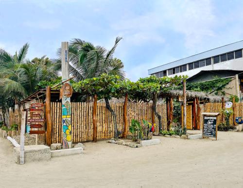 a wooden fence with a sign in front of a building at Hostal Olmito Canoa in Canoa