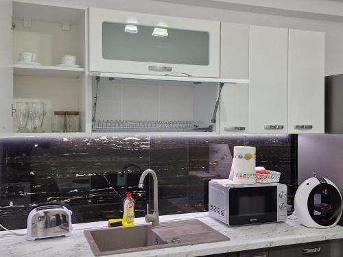 a kitchen with white cabinets and a sink and a microwave at Apartament Rezidențial in Suceava