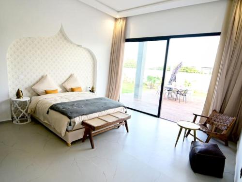 a bedroom with a bed and a large glass window at Villa Alanaé piscine chauffée in Douar Bellouk
