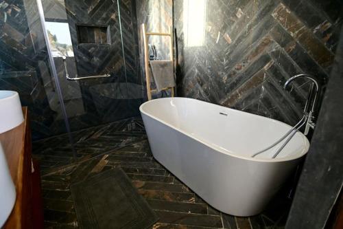 a bath tub in a bathroom with a stone wall at Villa Alanaé piscine chauffée in Douar Bellouk