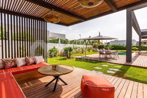 an outdoor patio with a red couch and a table at Villa Alanaé piscine chauffée in Douar Bellouk