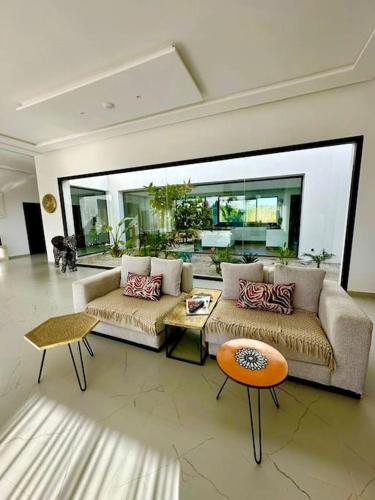 a living room with two couches and two tables at Villa Alanaé piscine chauffée in Douar Bellouk