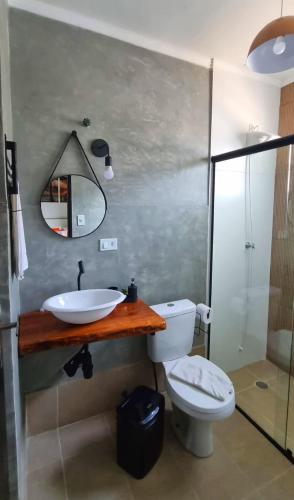 a bathroom with a sink and a toilet and a mirror at Recanto Isla Pousada in Ubatuba