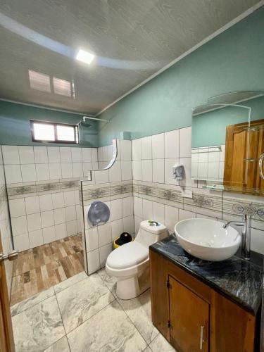 a bathroom with a white toilet and a sink at Cabinas La Catarata in Fortuna
